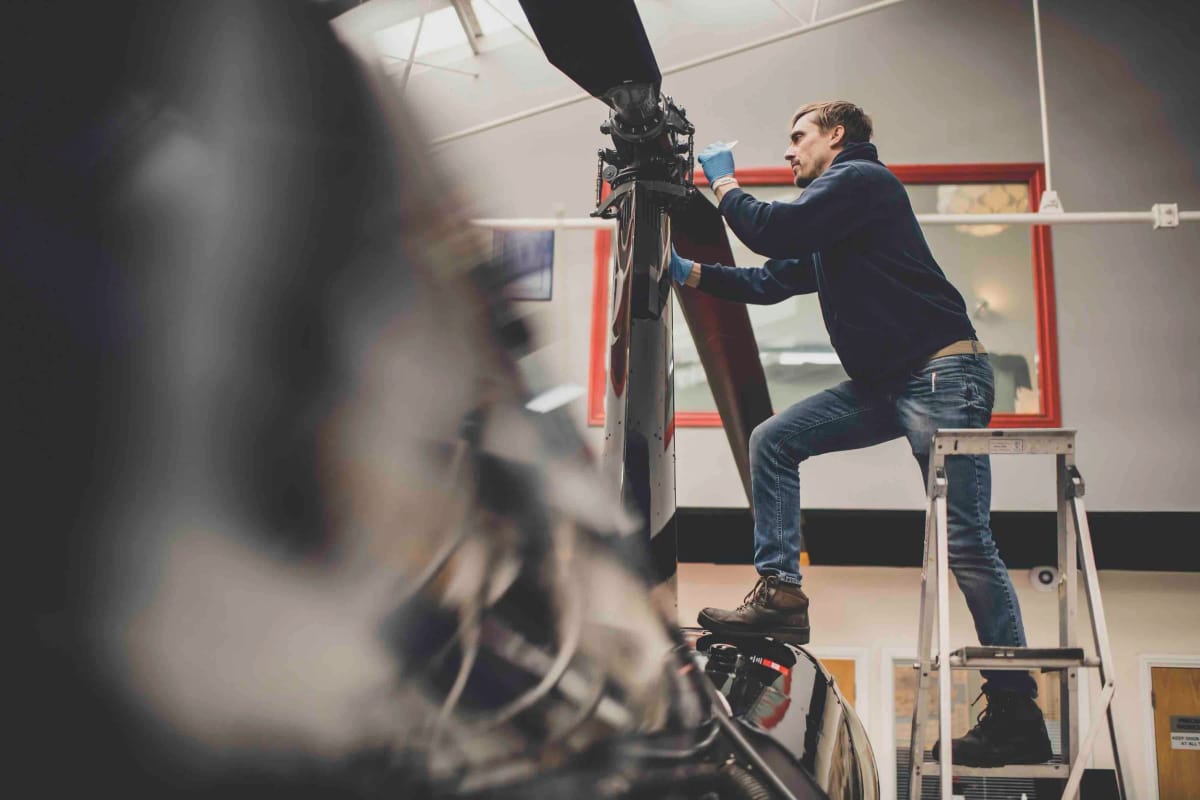An HQ Aviation engineer servicing a Robinson rotor head in the hangar at Denham